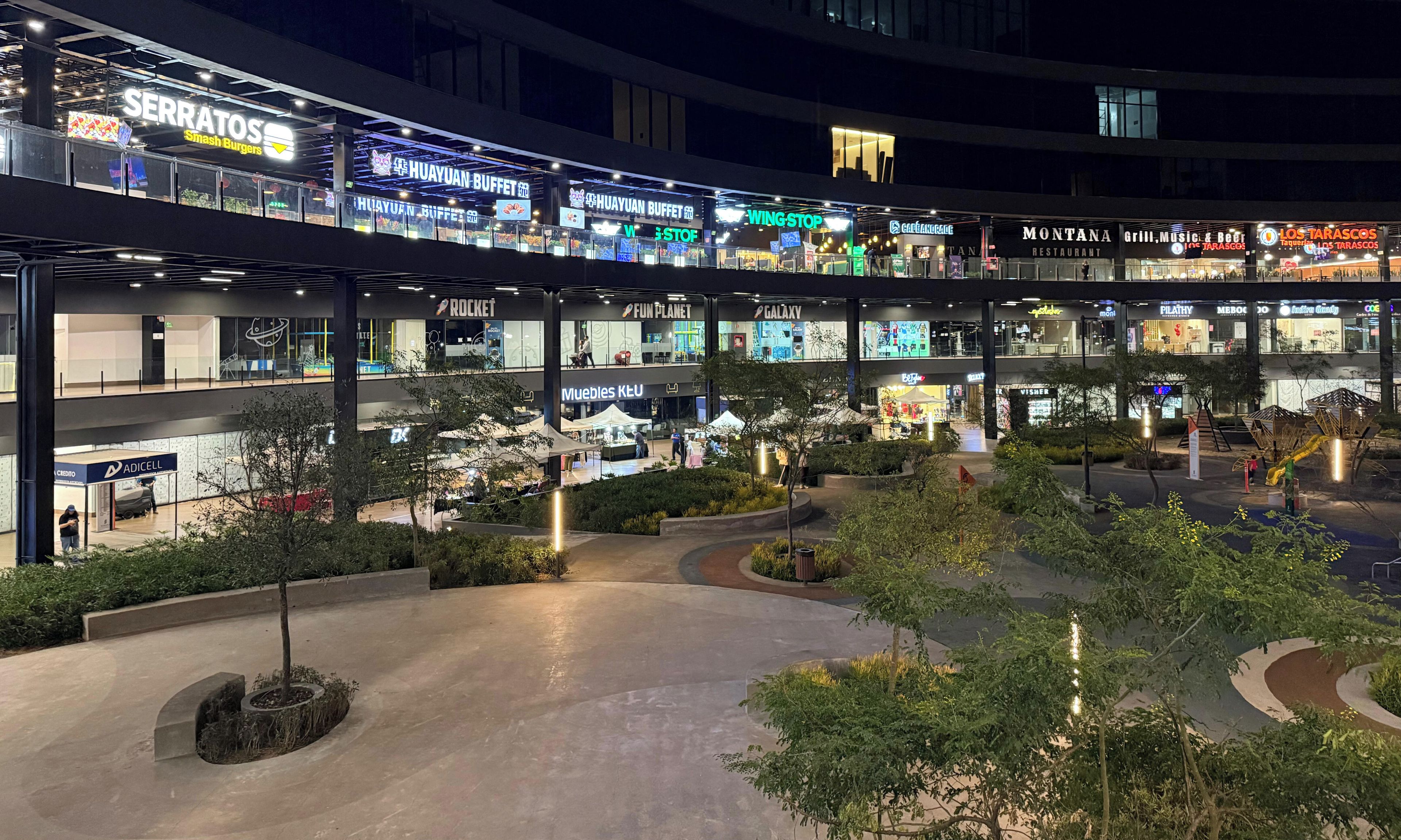Un centre commercial à plusieurs niveaux, comprenant divers magasins et une place centrale ouverte.