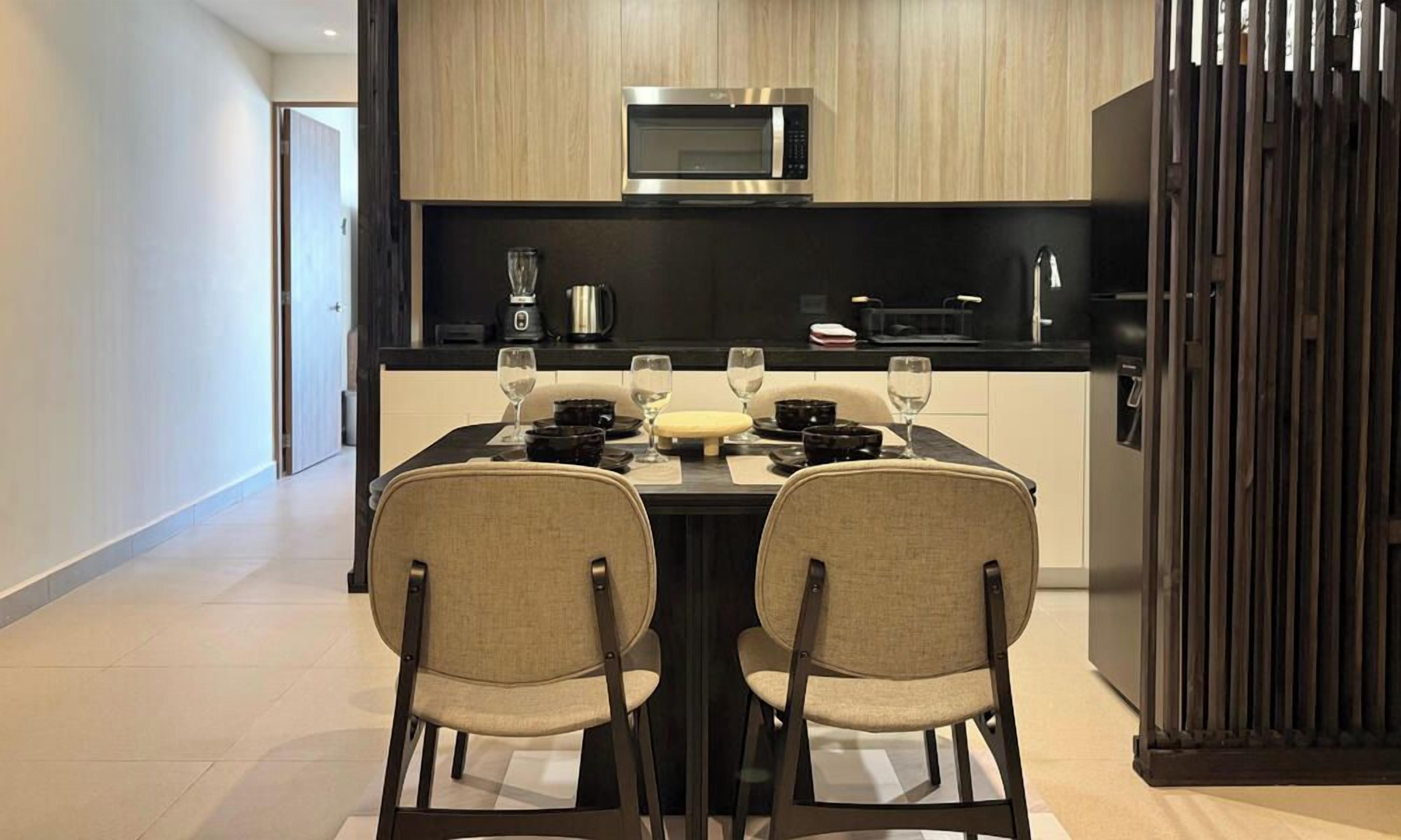 A modern kitchen with a dining table, chairs, a microwave, and a coffee machine.