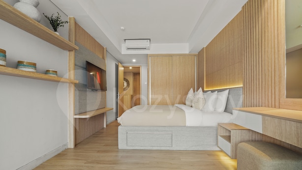 A modern bedroom with a bed, bedside tables, a wardrobe, and a shelf with decorative items. - Galia by Kozystay - Nusa Dua (South Kuta)