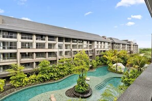 Un hotel con piscina rodeada de abundante vegetación y un cielo azul despejado.