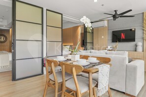 Una sala de estar moderna con comedor, un juego de sofá, un televisor de pantalla plana y un ventilador de techo.