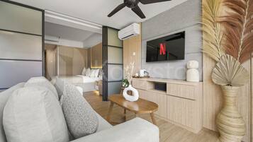 A modern living room with a sofa, coffee table, and a flat-screen TV mounted on the wall.