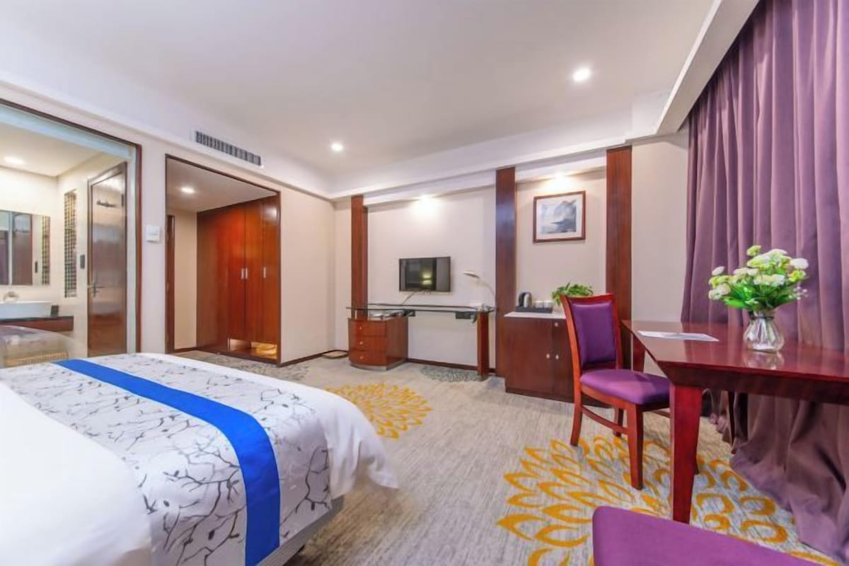 Una habitación de hotel con cama, escritorio, silla y televisor.