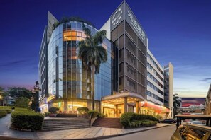 Un hotel moderno con fachada curva, entrada destacada e iluminación exterior.