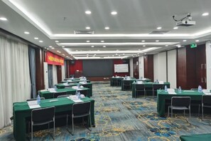 Un salón de conferencias con varias mesas, sillas y una pantalla de proyección.