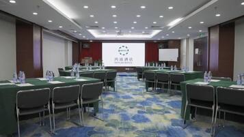 A conference room with multiple tables and chairs, a projector screen, and a presentation on the wall.