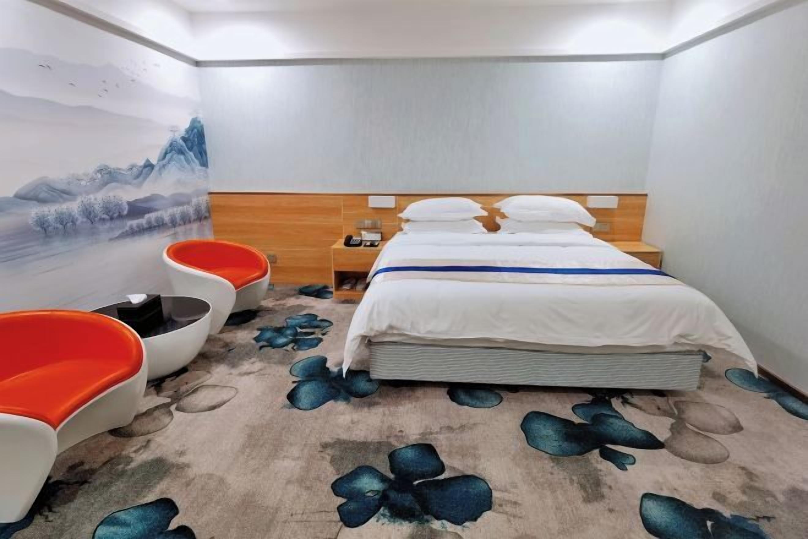 A hotel room with a bed, nightstands, a wall-mounted TV, and a seating area with chairs.