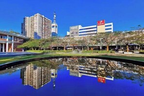 A cityscape with a reflection in a body of water, featuring modern buildings and a clear sky.