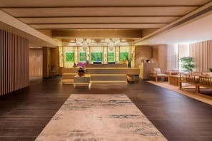 Un vestíbulo de hotel con una recepción, zona de estar y un amplio suelo alfombrado.