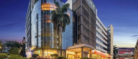 A modern hotel with a curved glass facade, a prominent entrance with steps, and a well-lit exterior.