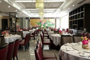 Un comedor con mesas redondas, sillas y centros de mesa florales.