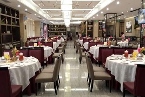 Un restaurante con varias mesas y sillas, un candelabro y un suelo pulido.