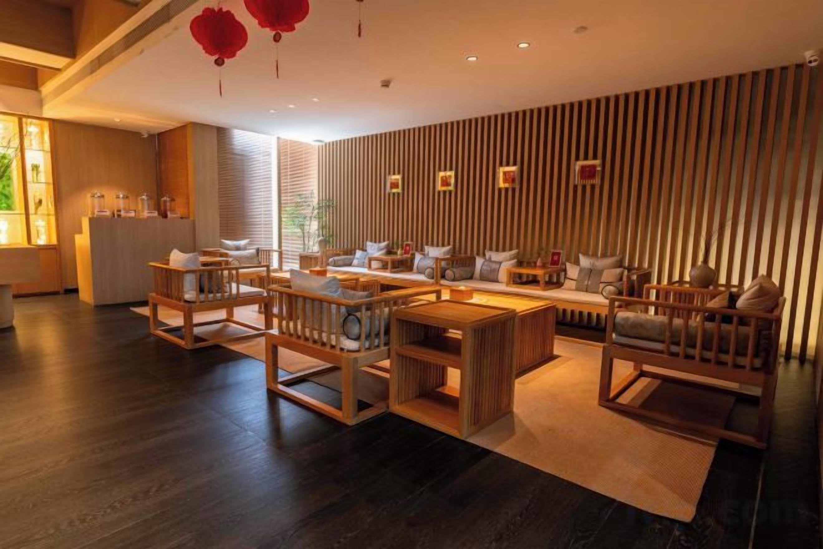 Un interior moderno con suelo de madera, una zona de estar con sofás y sillones, y una cocina con encimera y electrodomésticos.