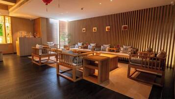Un interior moderno con suelo de madera, una zona de estar con sofás y sillones, y una cocina con encimera y electrodomésticos.