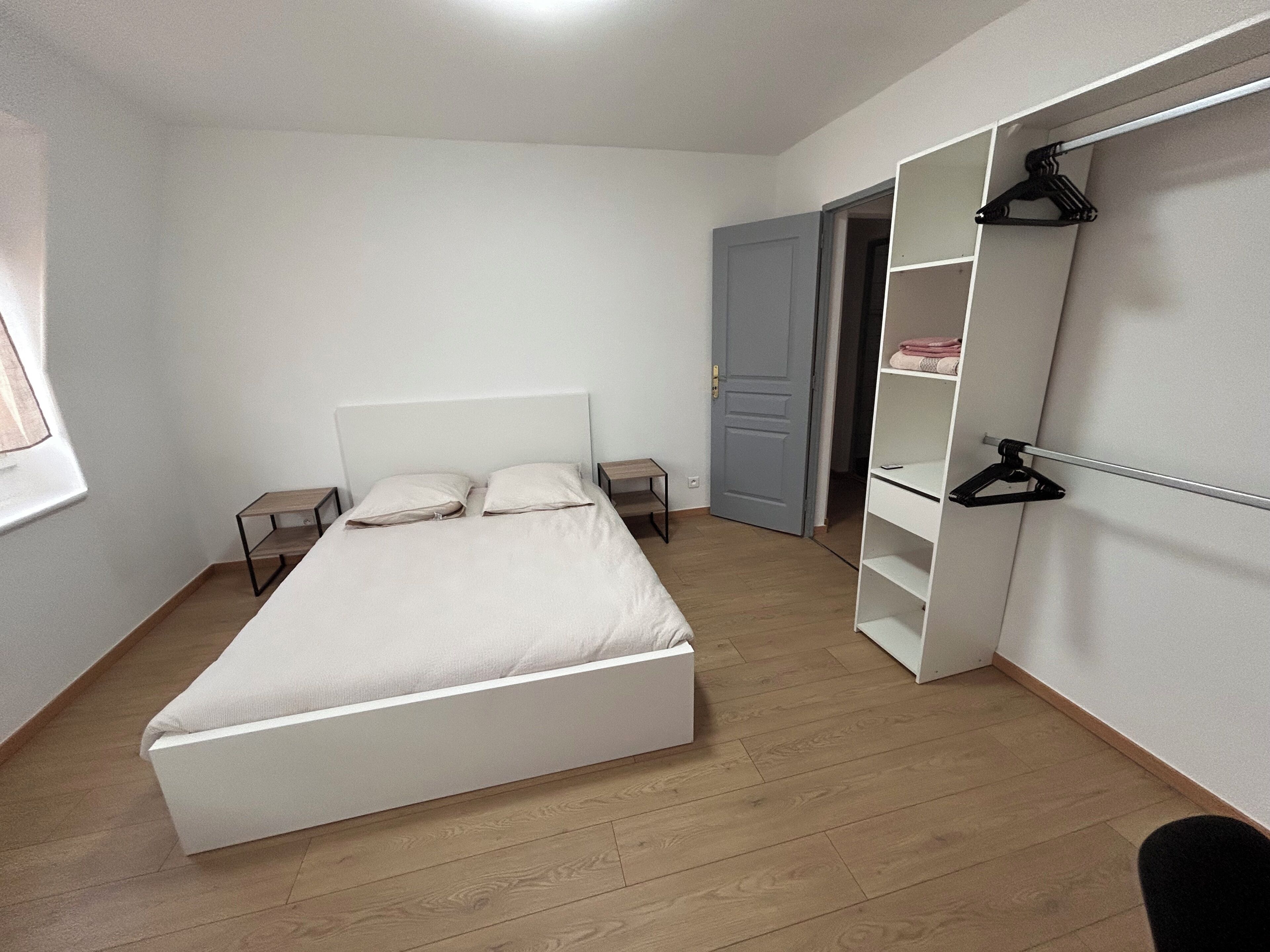Een slaapkamer met een bed, een kledingkast en een deur naar een andere kamer.