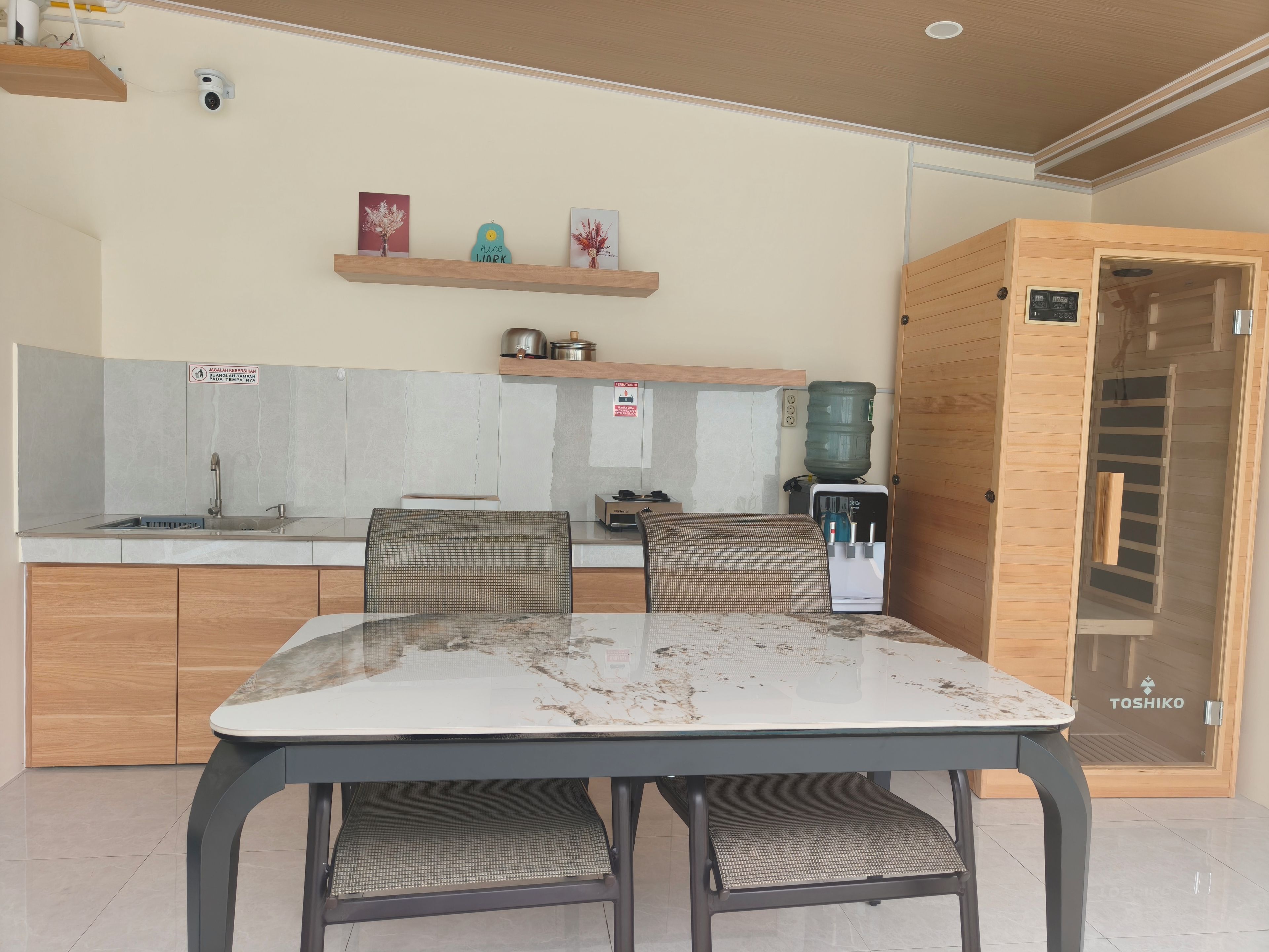 Une cuisine moderne avec une table à manger, des chaises, un distributeur d’eau et un meuble en bois.