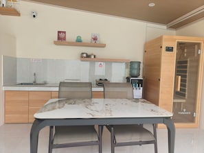 Una cocina moderna con una mesa de comedor, sillas, dispensador de agua y un armario de madera.