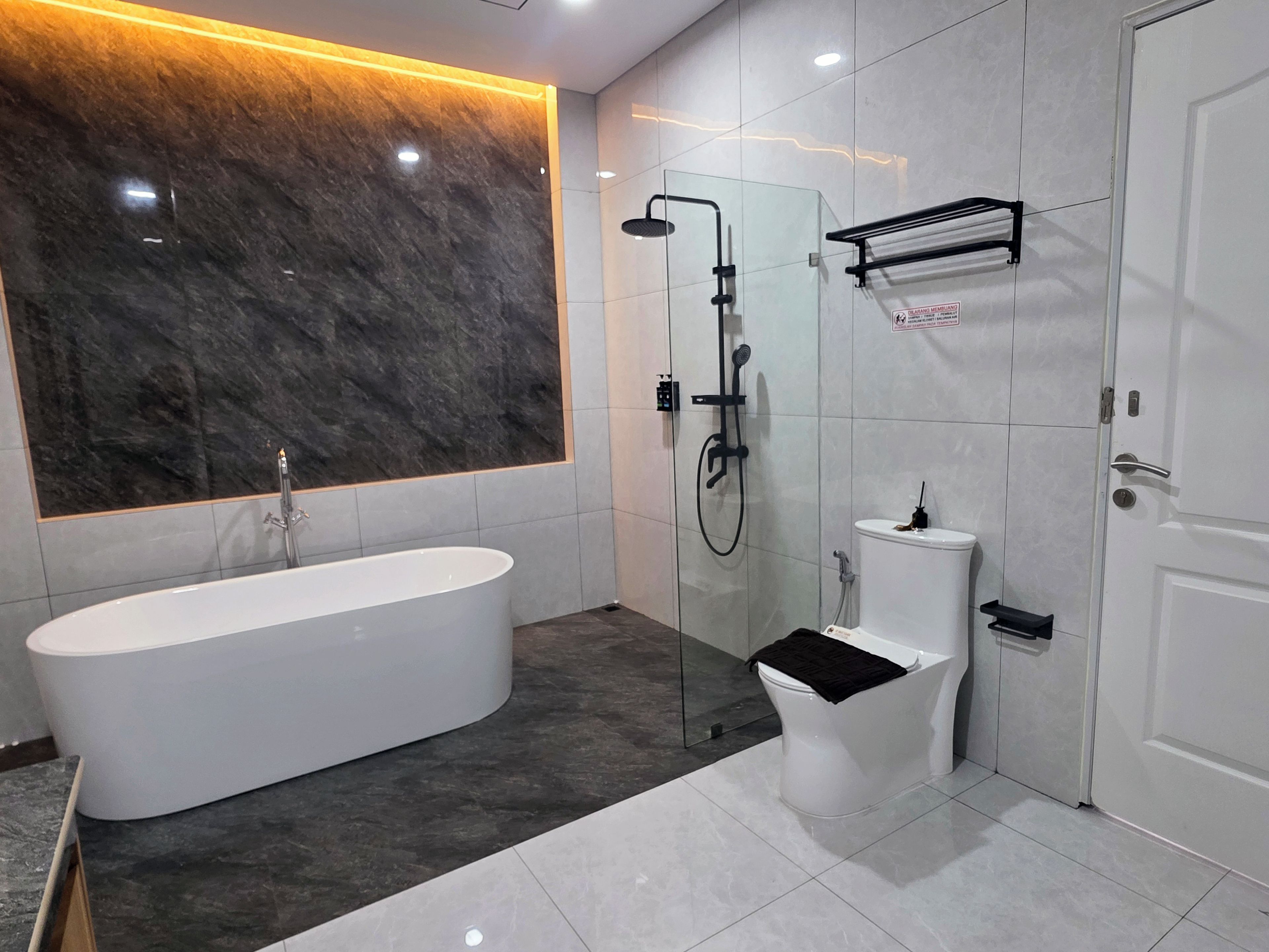 Un baño moderno con una bañera independiente, ducha con mampara de vidrio y un inodoro.