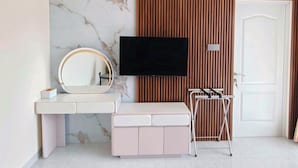 A modern bathroom with a vanity, a mirror, a television, and a door.
