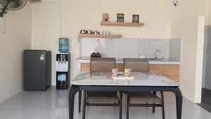 A modern kitchen with a dining table, chairs, a water dispenser, and a refrigerator.
