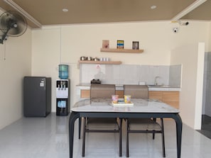 Una cocina moderna con mesa, sillas, dispensador de agua y refrigerador.