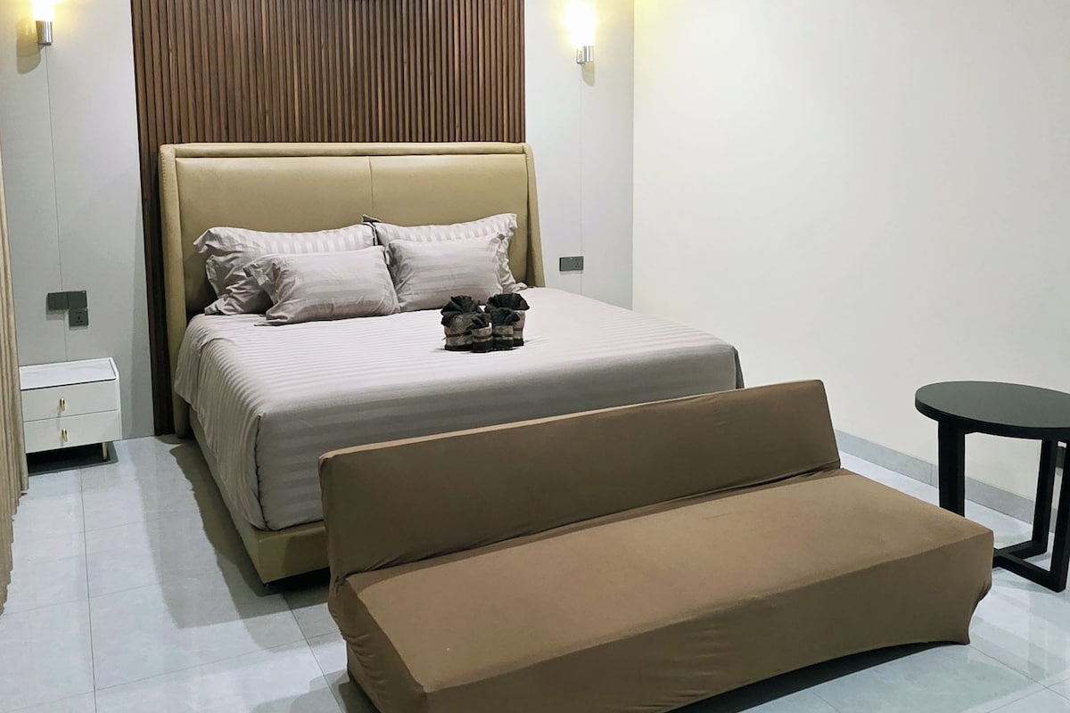 Un dormitorio moderno con cama, sofá, ventilador de techo y aire acondicionado.