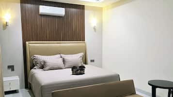 A modern bedroom with a bed, a sofa, a ceiling fan, and an air conditioning unit.