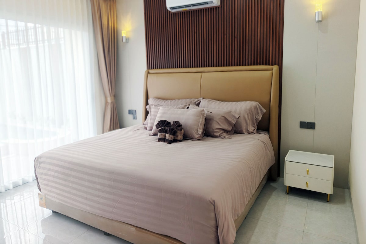 Un dormitorio moderno con una cama grande, una mesita de noche y un equipo de aire acondicionado en la pared.