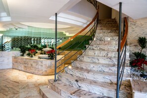 A marble staircase with a wooden handrail, leading to a glass-enclosed upper level. - Mediterranean Apartment in El Higuerón, Fuengirola – Your Peaceful Oasis (Fuengirola)