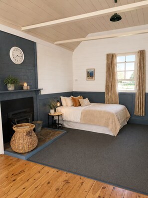 A bedroom with a bed, a fireplace, a clock, and a window with curtains.