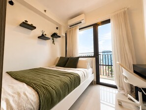 Ein modernes Schlafzimmer mit Bett, Schreibtisch und Balkon mit Blick.