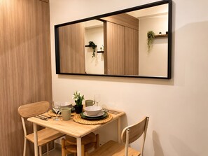 A dining area with a wooden table, chairs, a mirror, and a potted plant. - Modern & Fully Equipped Condo - near MOA Pasay with Washer-Dryer (Pasay City)
