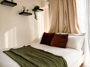 Ein Schlafzimmer mit einem Bett, Kissen, einer Decke und Wandregalen mit Pflanzen.
