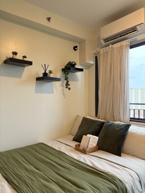 A bedroom with a bed, pillows, a bedside table, a window with curtains, and wall-mounted shelves with plants. - Modern & Fully Equipped Condo - near MOA Pasay with Washer-Dryer (Pasay City)