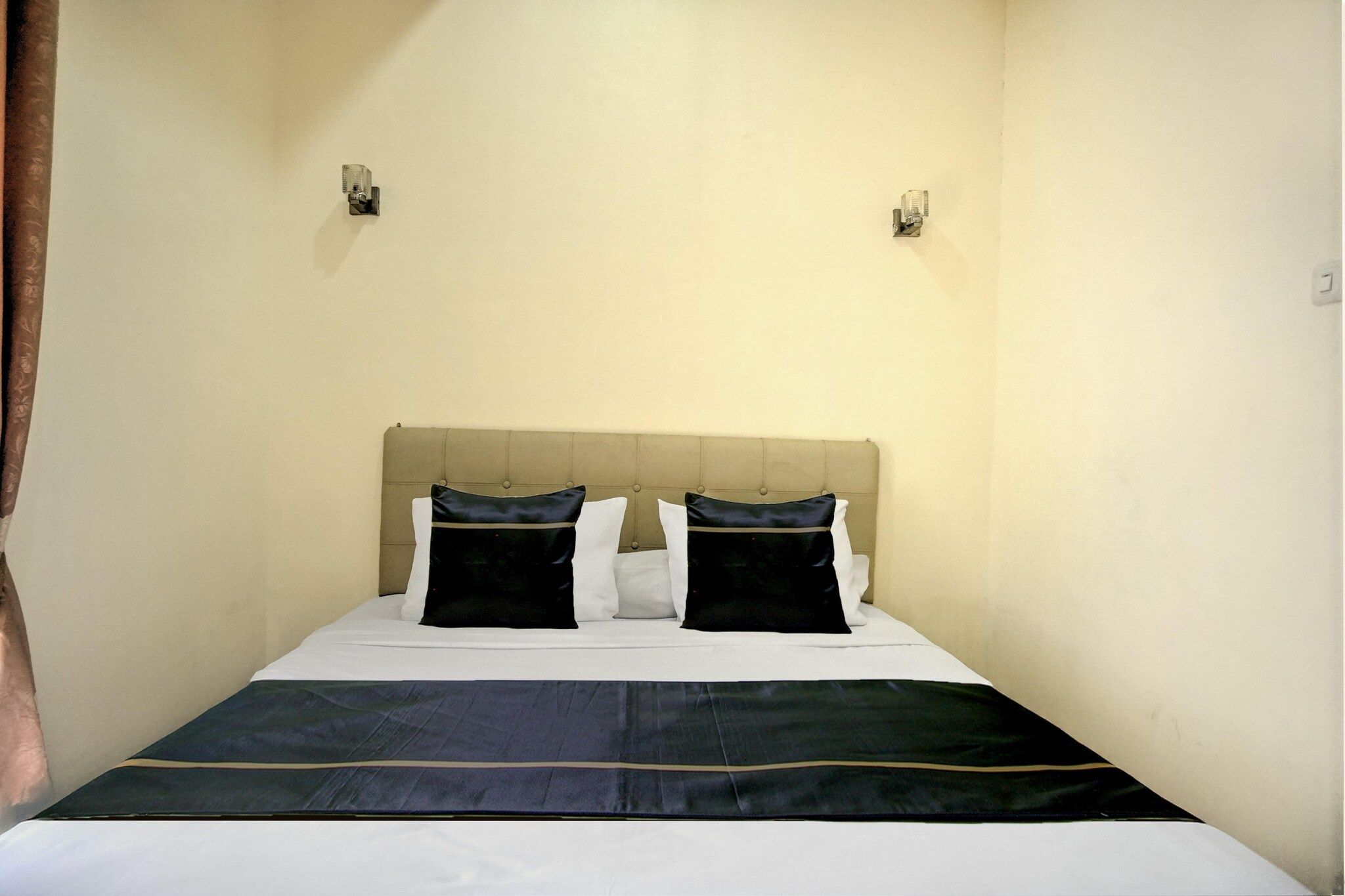 Ein Einzelbett mit Kopfteil, zwei Wandleuchten und eine schlichte Wand.