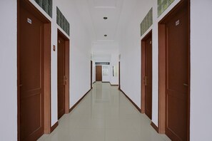 Un long couloir étroit, avec des portes des deux côtés, numérotées 101 et 110, qui donnent accès à des pièces.