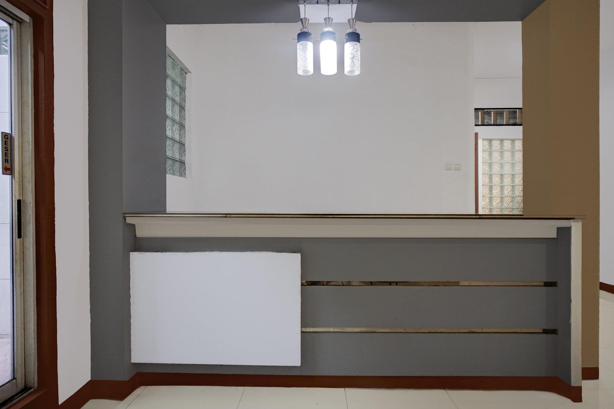 A room with a white wall, a wooden bench, and a glass door.