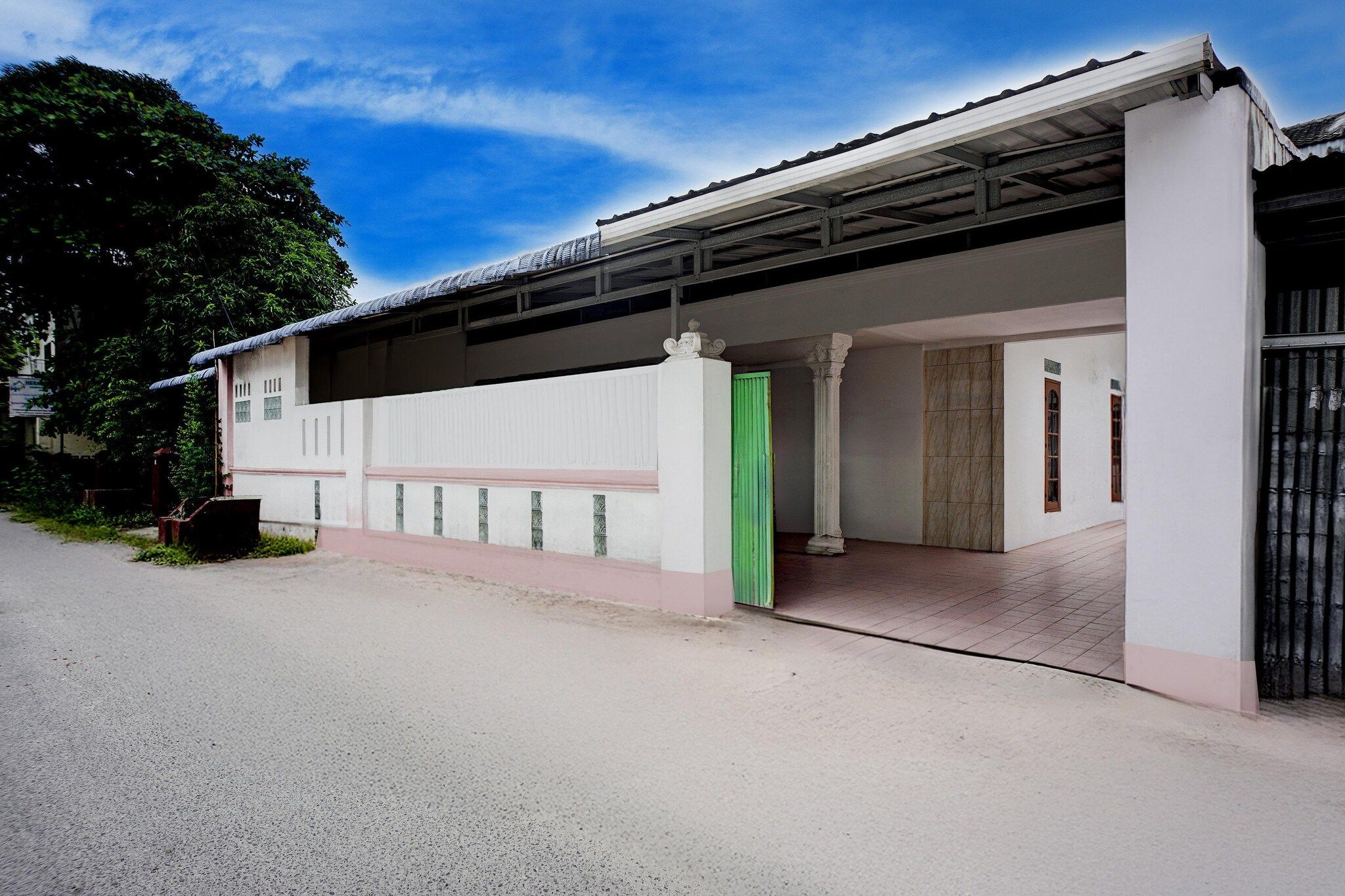 A building with a covered entrance, a gated driveway, and a clear sky.
