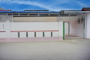 Ein Gebäude mit weißer Fassade, einem rot-weißen Markisenstreifen und einer grünen Tür.