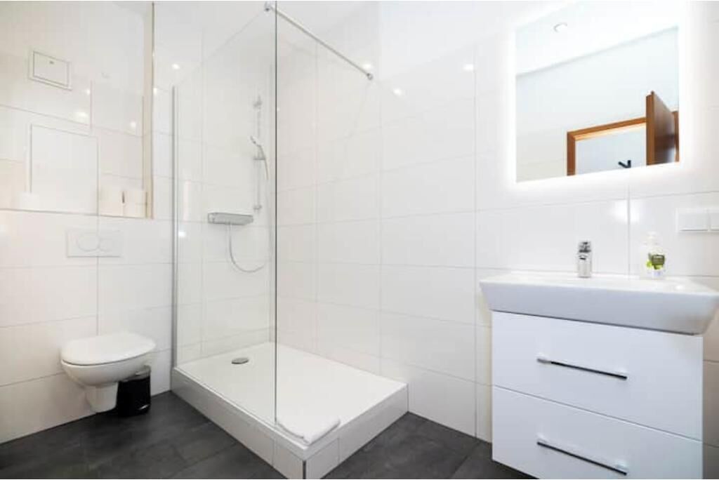 A modern bathroom with a glass-enclosed shower, a white toilet, and a vanity with drawers.
