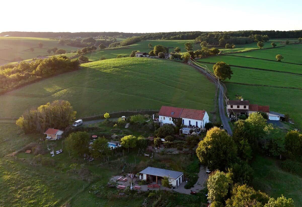 Propiedad rural con casa principal, construcciones más pequeñas y un área cercada con árboles.