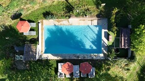 An aerial view of a swimming pool with adjacent lounge chairs and umbrellas, surrounded by greenery. - Charming & cosy French studio with pool in Digoin (Digoin)