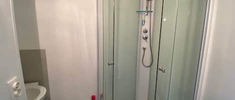 En duschkabin med glasväggar, utrustad med ett duschmunstycke som kan hållas i handen och ett handhållet duschmunstycke.