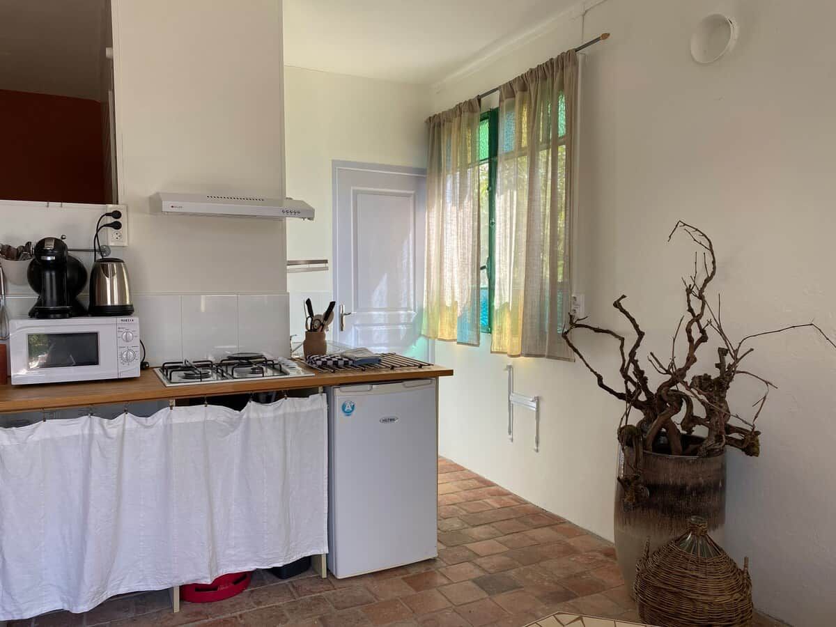 Cocina compacta equipada con microondas, estufa a gas y refrigerador pequeño.