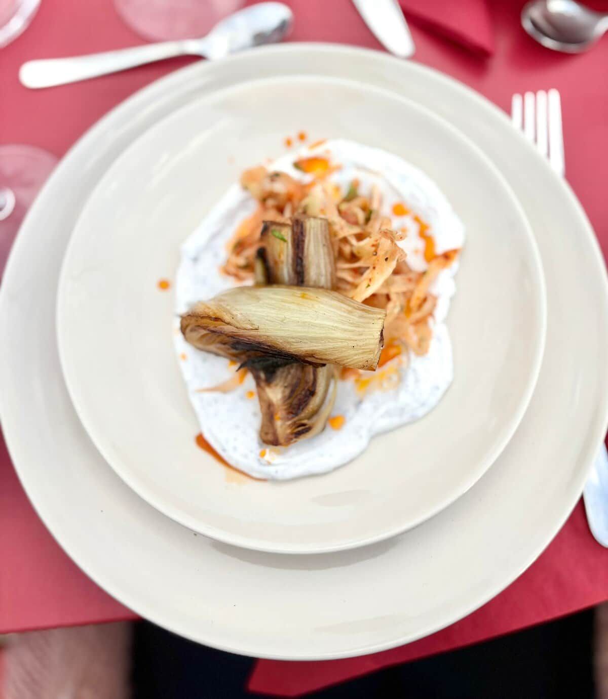 A plate with a food item, possibly a dish with shredded vegetables and a piece of meat, on a white plate.