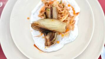 A plate with a food item, possibly a dish with shredded vegetables and a piece of meat, on a white plate.