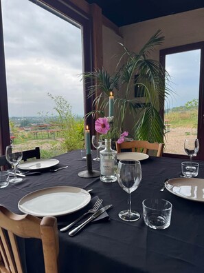 A dining table set for four with candles, a bottle of GinBey, and a view of the countryside. - Entire Property: 3 guesthouses. Sleeps 16 (Digoin)