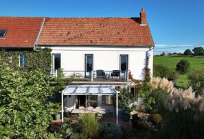 A two-story house with a red-tiled roof, a covered patio with outdoor furniture, and a garden with various plants and trees. - Entire Property: 3 guesthouses. Sleeps 16 (Digoin)