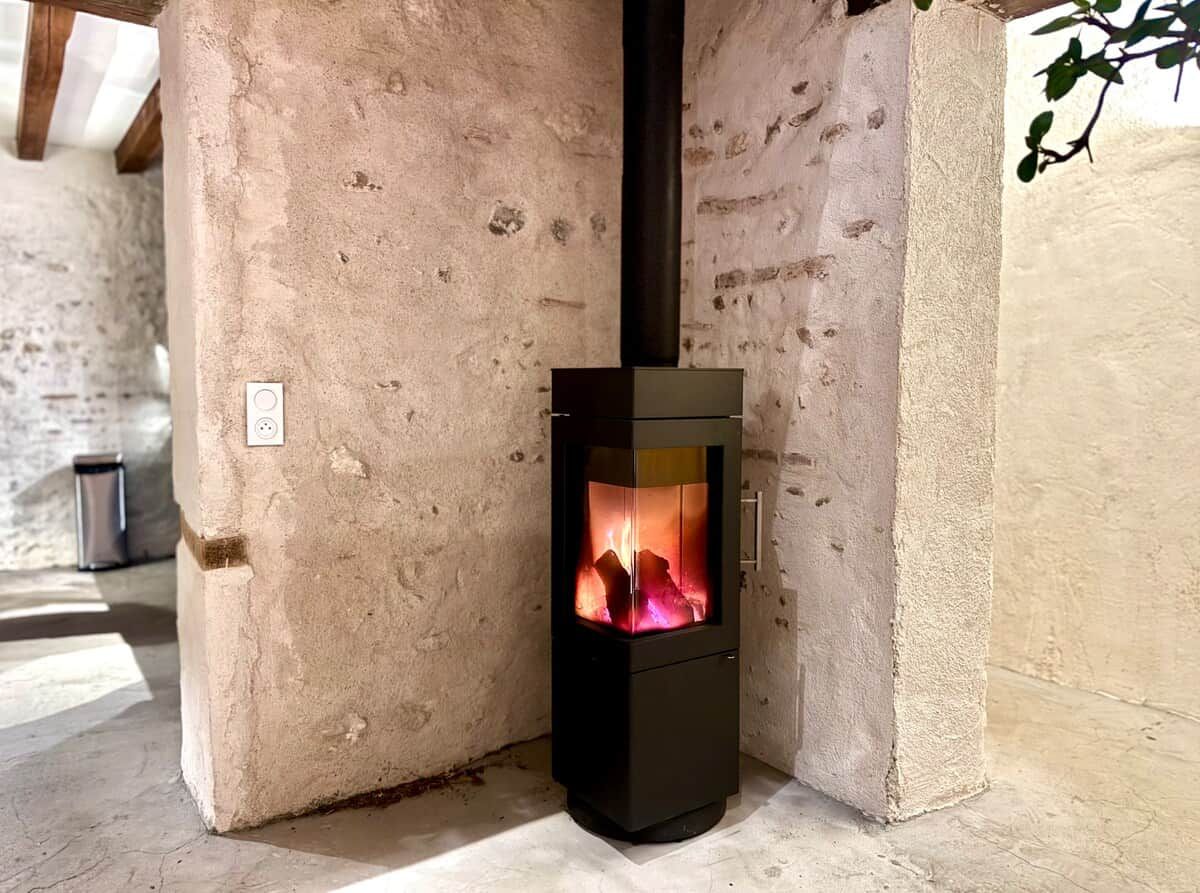 A wood-burning stove in a corner of a room with a textured wall.