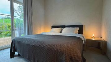 Een slaapkamer met een bed, nachtkastjes en uitzicht door een groot raam.